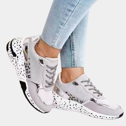 Dames sneakers in goud en beige met glinsterende details, zwarte en witte zool, en veters. Modieuze sportschoenen voor casual en sportieve outfits.
