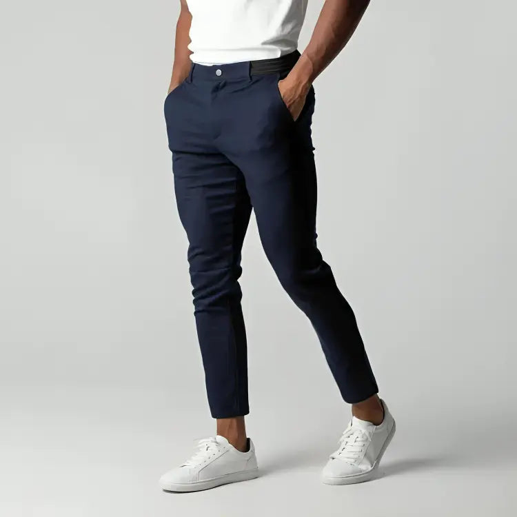 Pantaloni chino beige da uomo, vestibilità slim, tasche laterali, abbinati a scarpe bianche e maglietta bianca. Moda casual elegante.